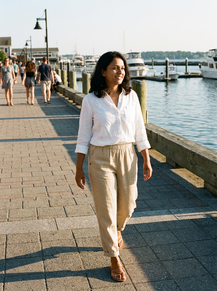 Woman wearing Bayside tapered linen pants on a waterfront promenade